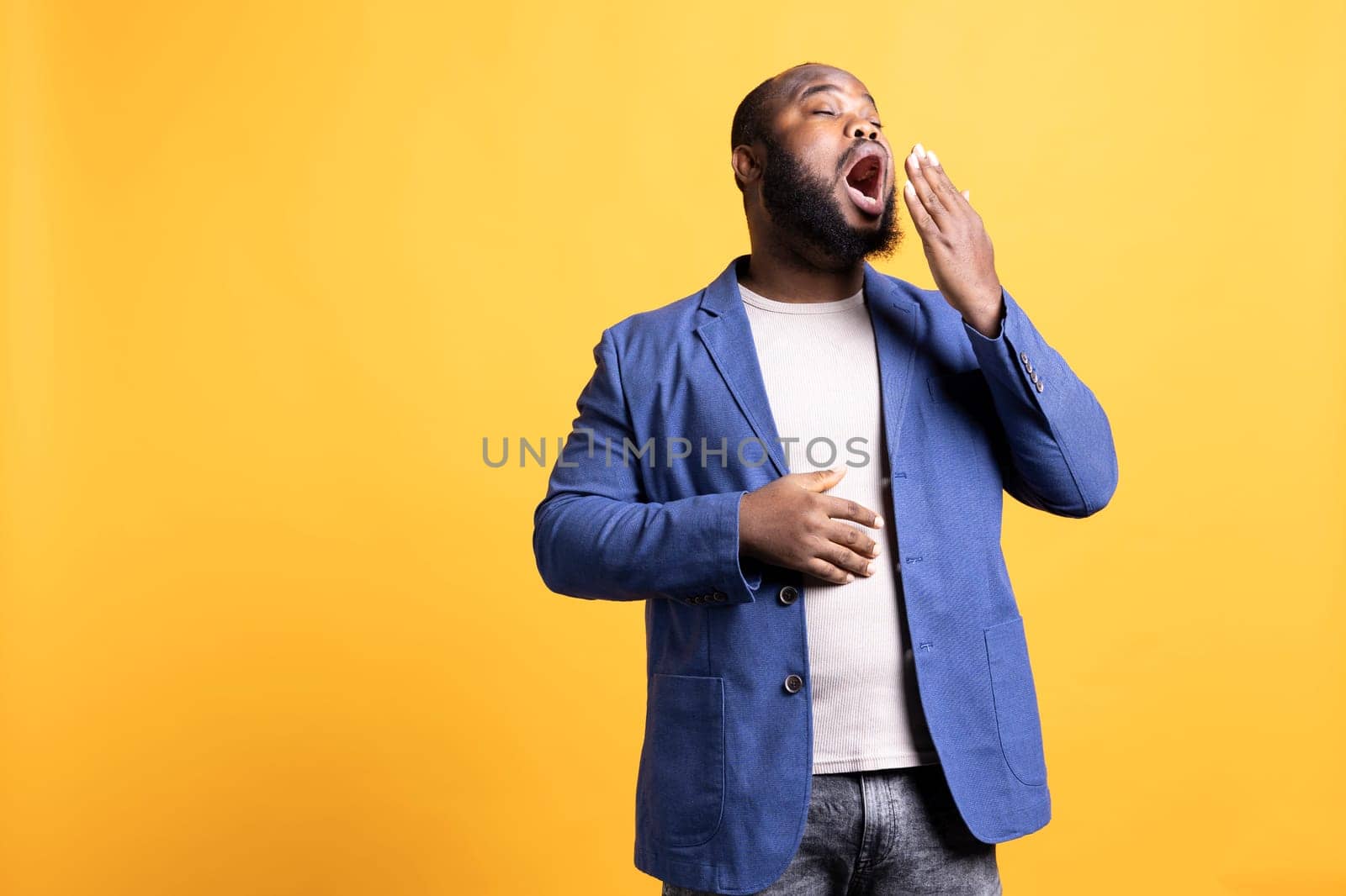 Man feeling exhausted and yawning, isolated over studio background by DCStudio