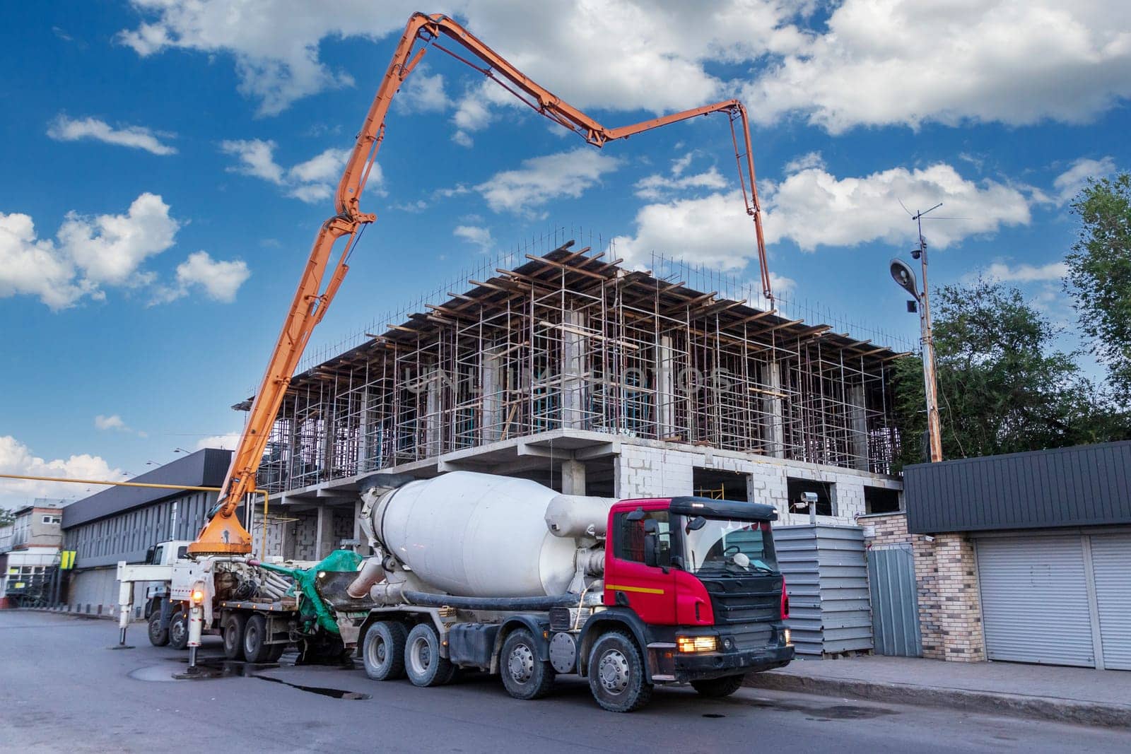 A concrete pump truck takes concrete from a concrete mixer truck and pours the floor at a construction site.