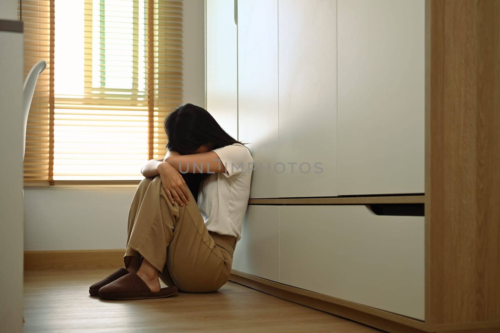 Upset teenage girl sitting on floor feeling lonely and sad. Psychological and mental health concept.
