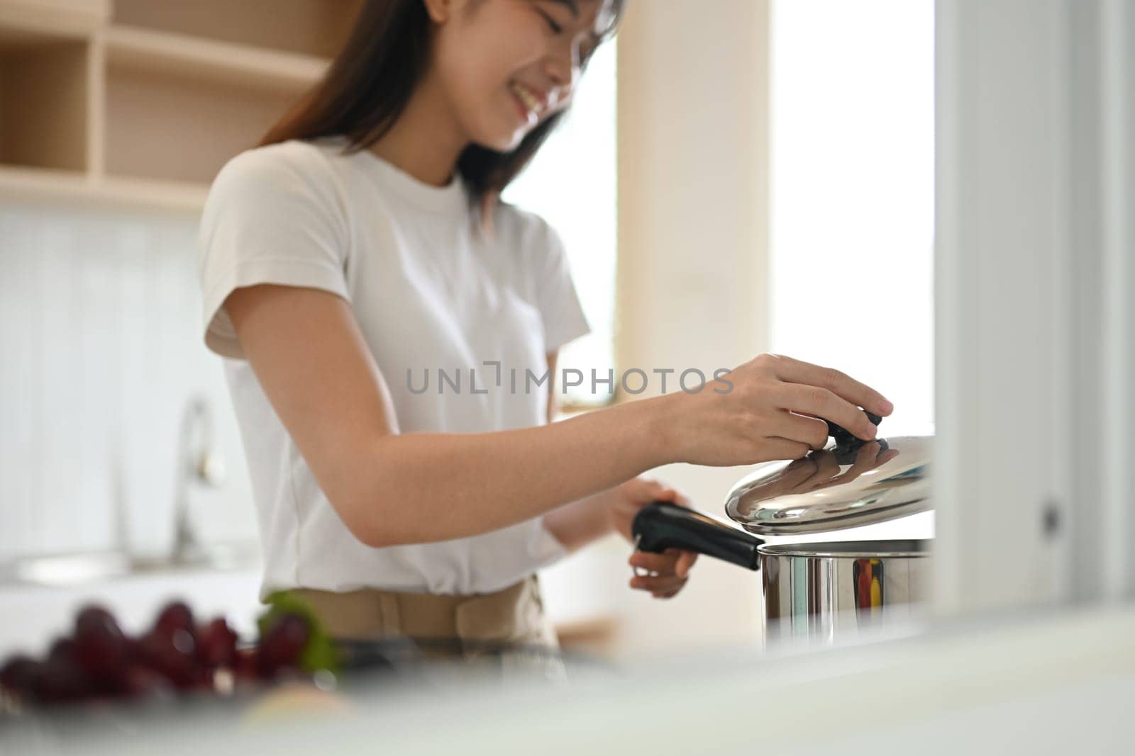 Shot of attractive young asian woman preparing soup in kitchen at home.