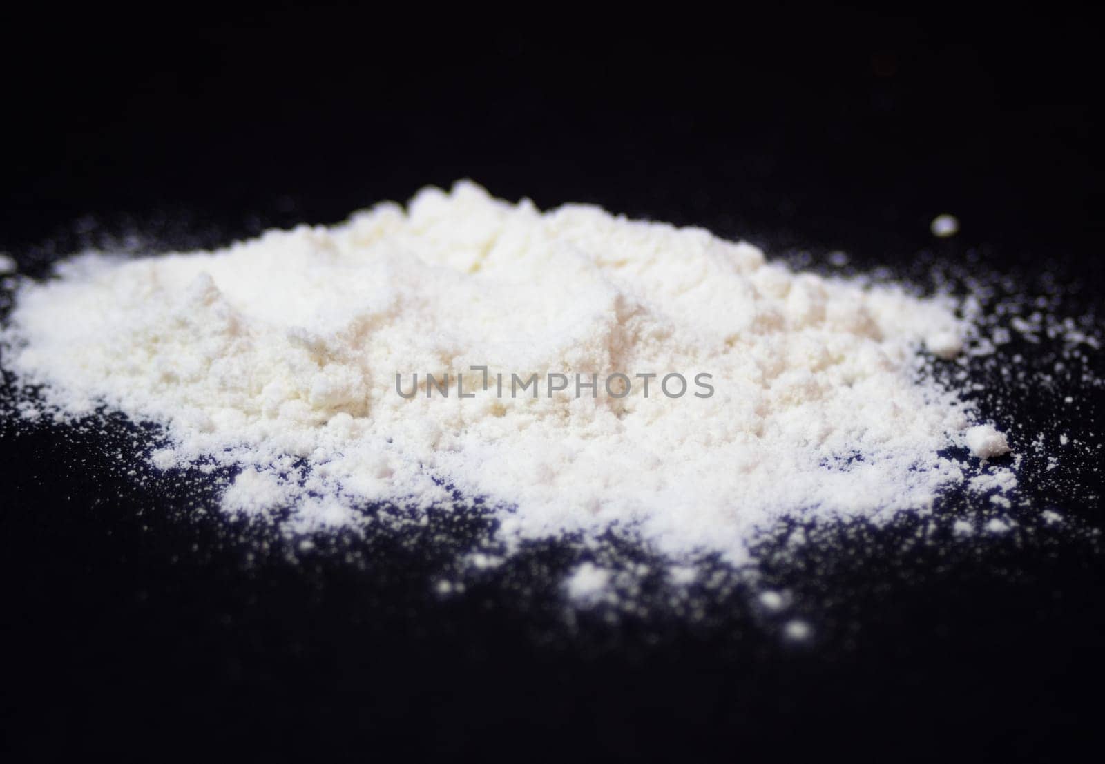 Wheat flour pile on a black background. Side view picture by VeroDibe