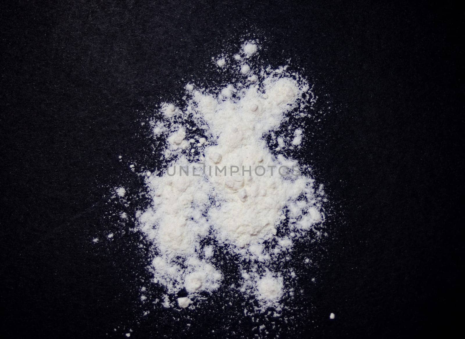 White flour scattered on a black background. Zenithal photo by VeroDibe