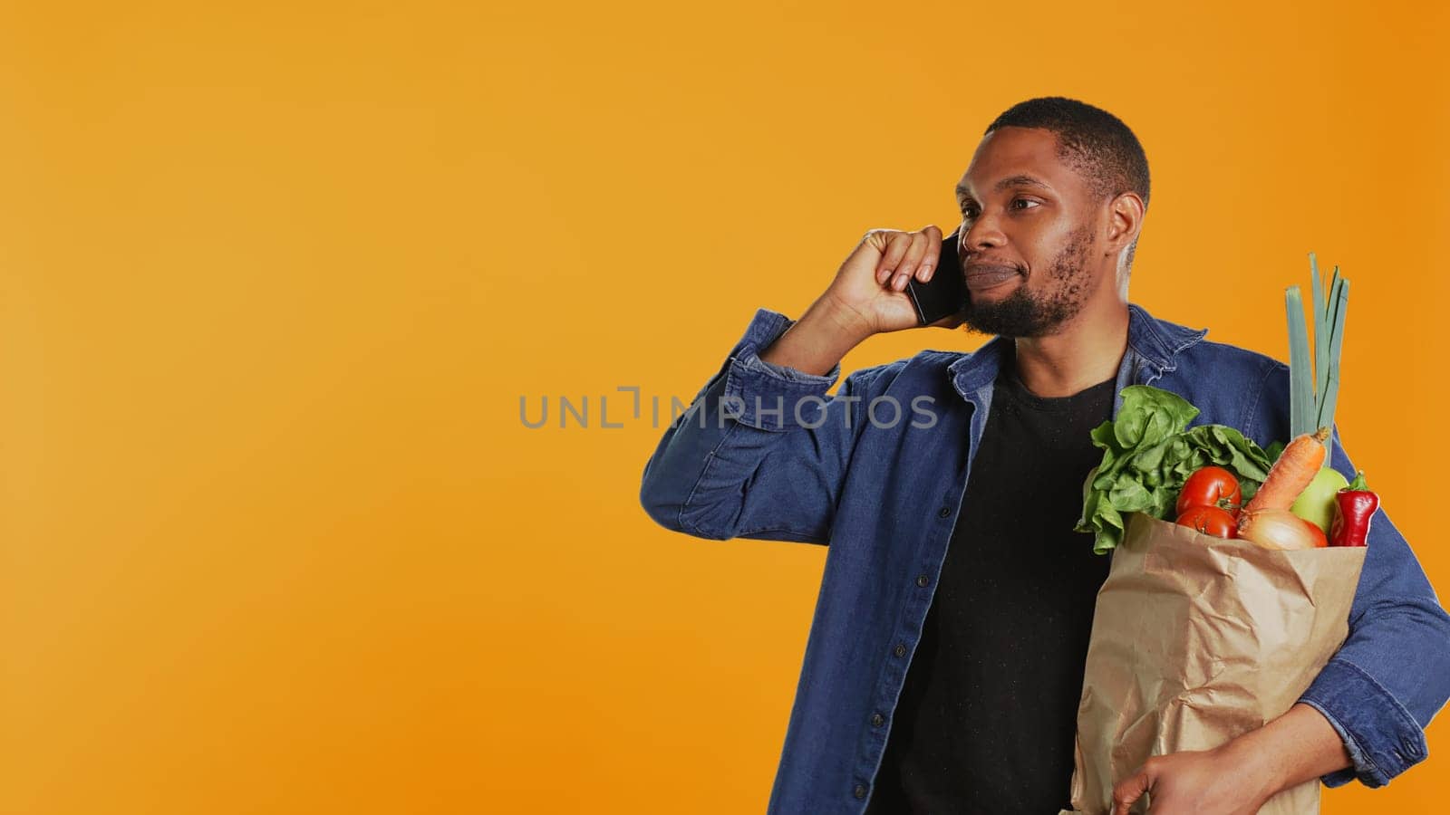 African american man on grocery shopping spree chatting on phone call by DCStudio