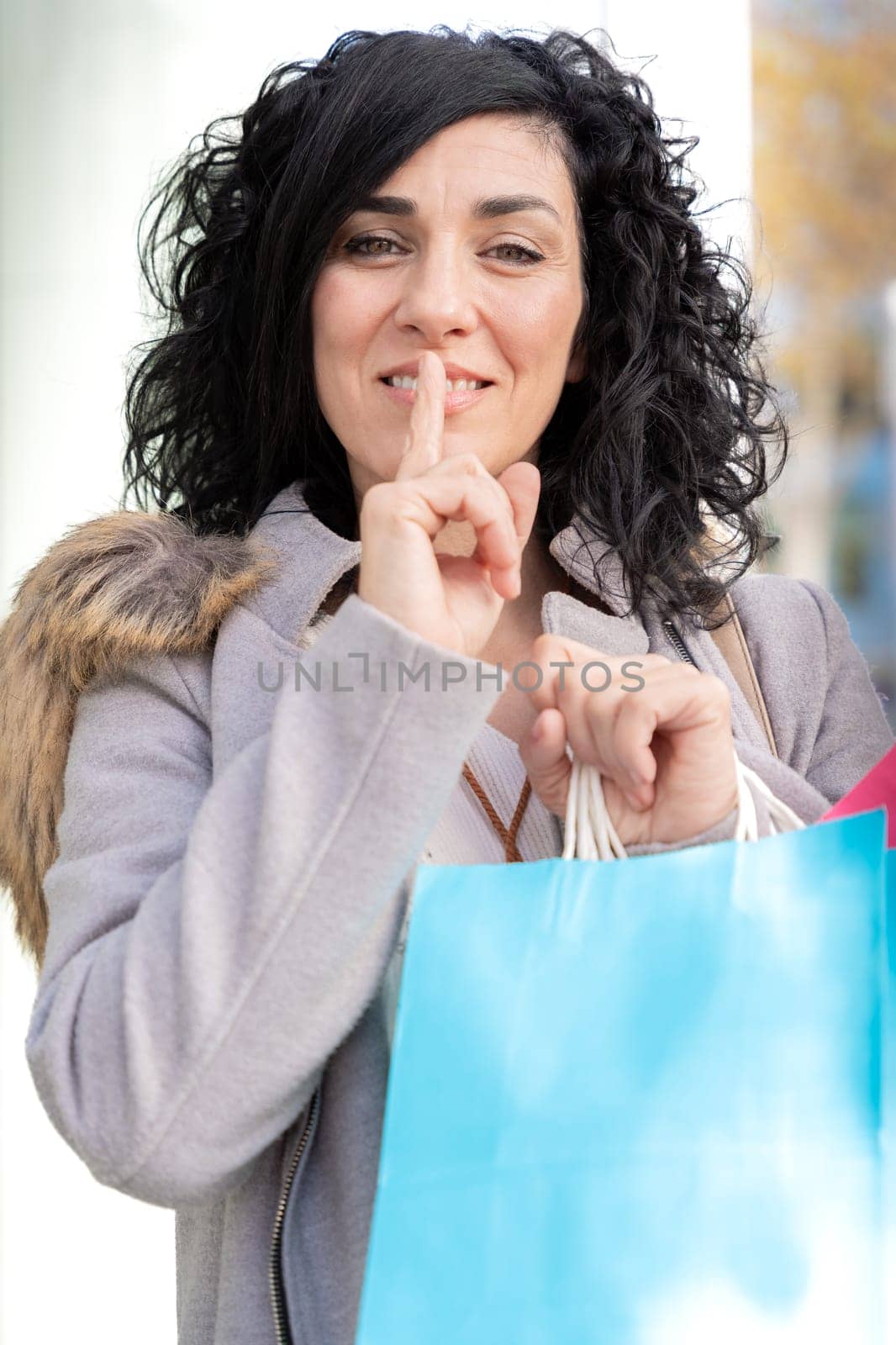 Smiling attractive young woman with shopping bags looking at camera.Vertical by mariaphoto3