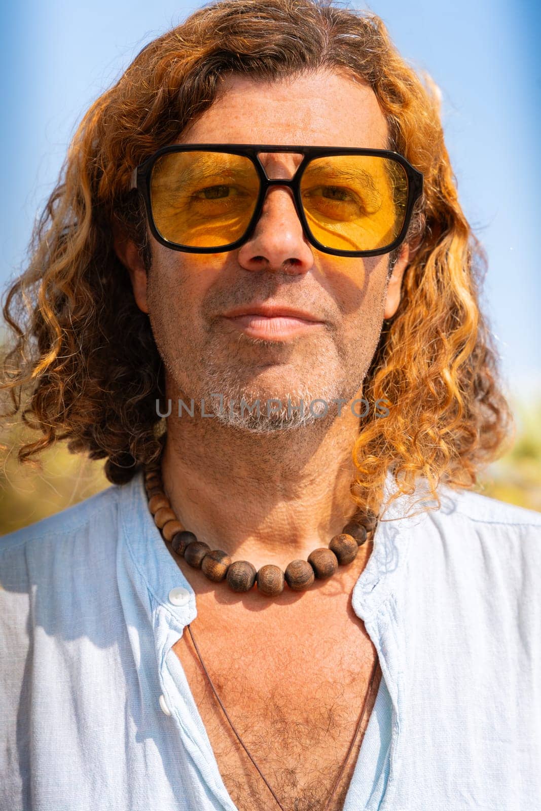 Caucasian adult man wearing smiling sunglasses looking at camera. Man on vacation on the coast.