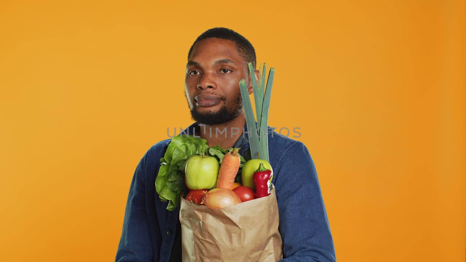Young adult accidentally dropping an apple from his paper bag full of ethically sourced fruits and veggies, buying a variety of organic homegrown goods. Support vegan lifestyle. Camera A.