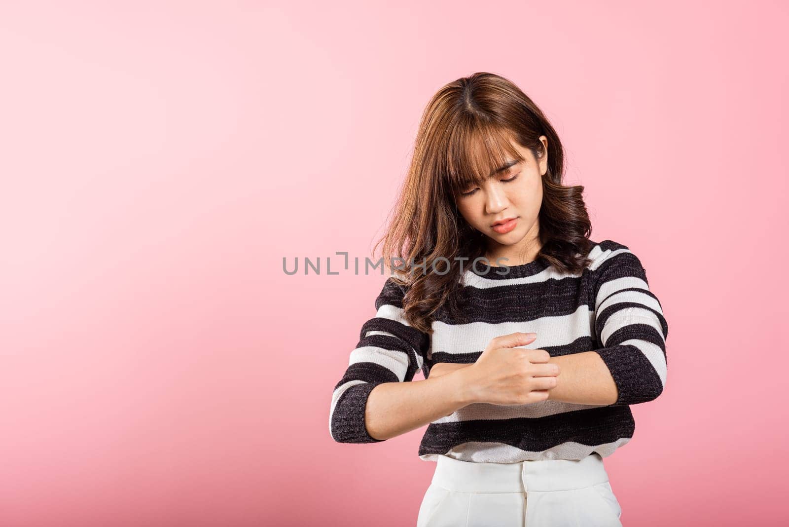Asian beautiful woman itching her scratching her itchy arm on pink background with copy space, Medical and Healthcare concept, female skin problems scratch the itch with her arm