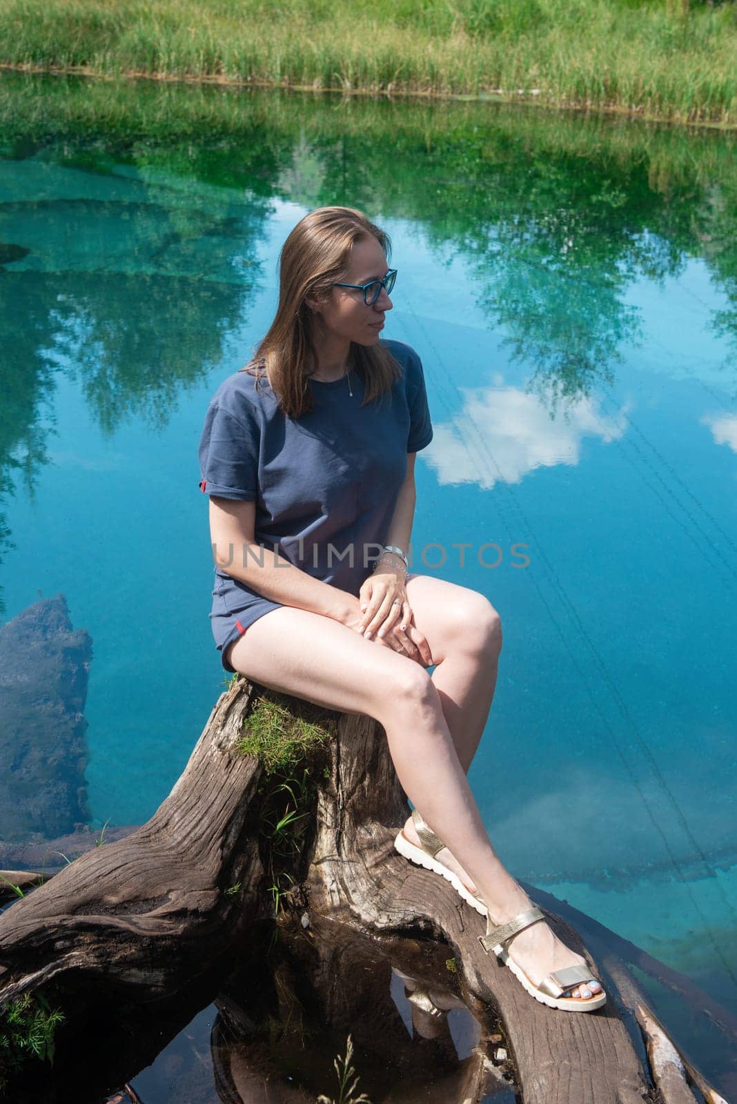 Woman at Beautiful Geyser lake with thermal springs that periodically throw blue clay and silt from the ground. Altai mountains, Russia