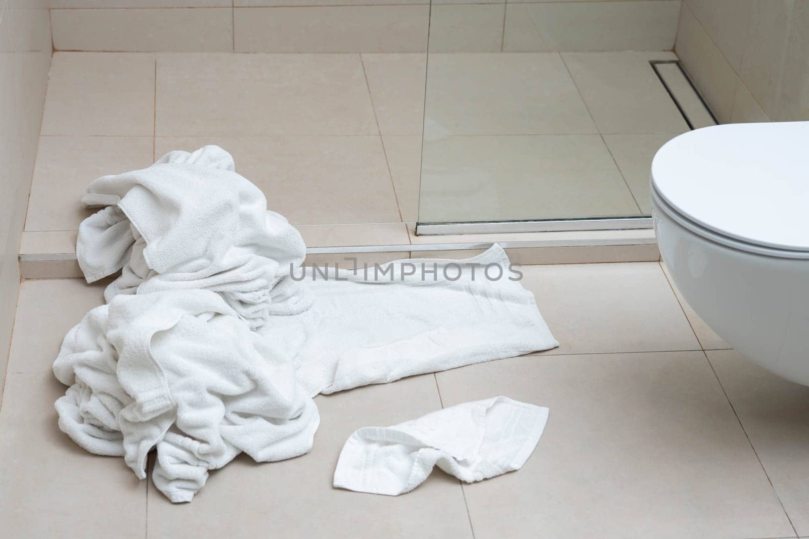 Pile of dirty used towels on the hotel bathroom floor. Housekeeping replace only the used towels on