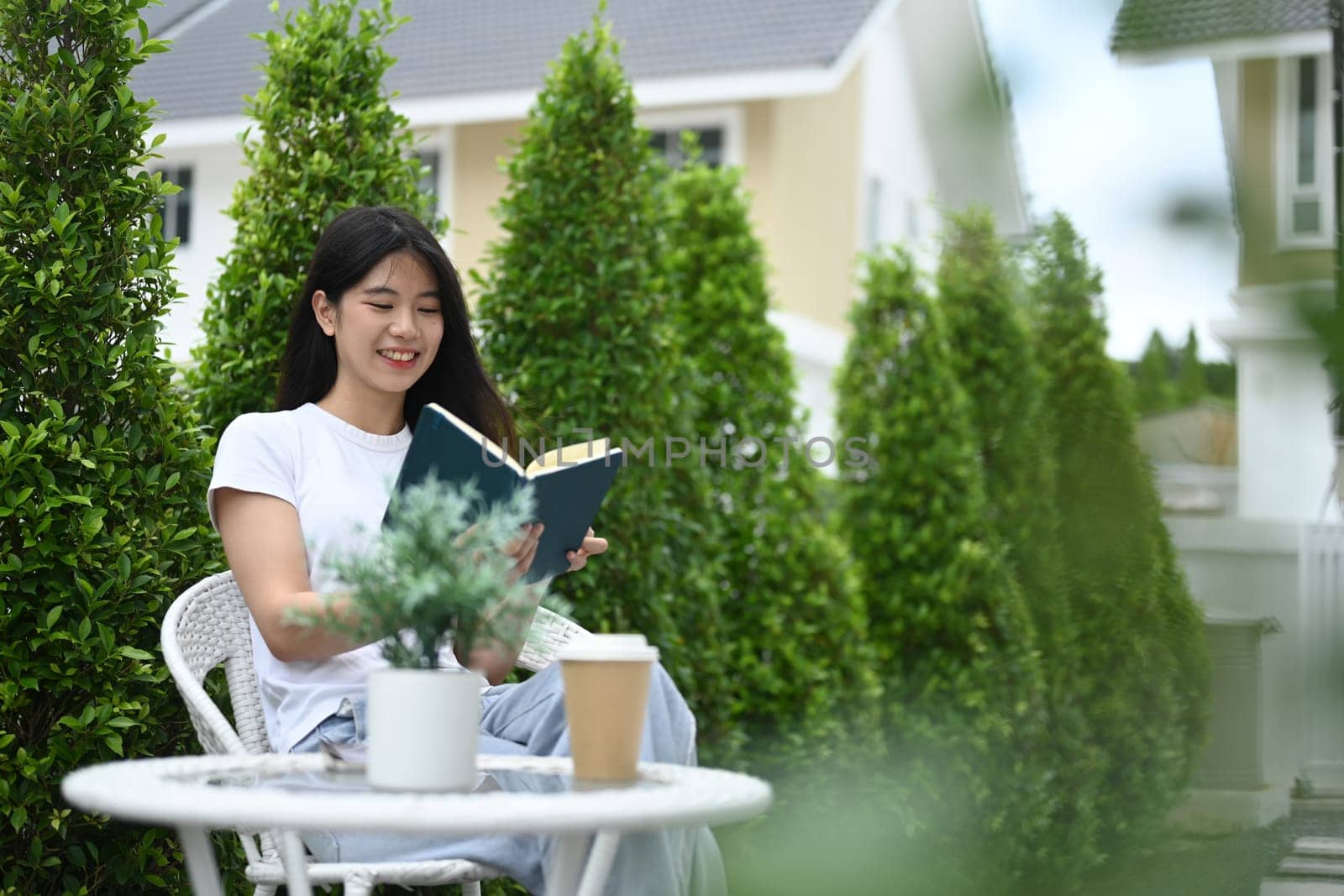Peaceful young Asian woman in casual clothes reading book in the garden feeling relax and happy.