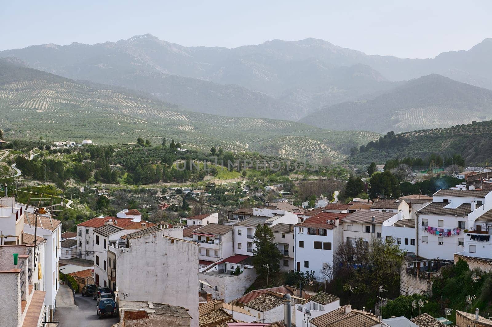 View of beautiful medieval district of Spanish village, Quesada in the region of Jaen, Andalusia, Spain in mountains. White houses with red tiles over mountain ridge background of La Sierra de Cazorla