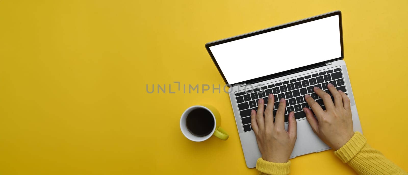 Woman hands typing on laptop keyboard over yellow background with copy space.