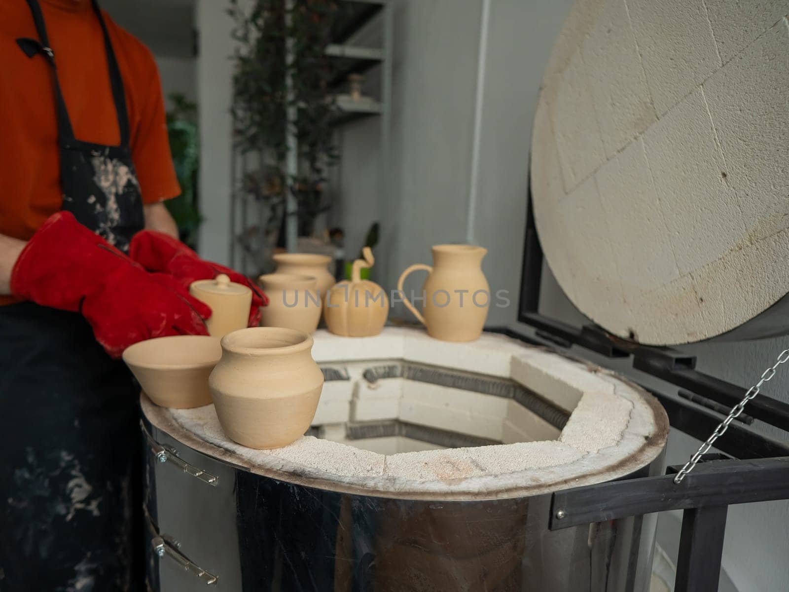 Close-up of a man's hands loading ceramics into a special kiln. by mrwed54