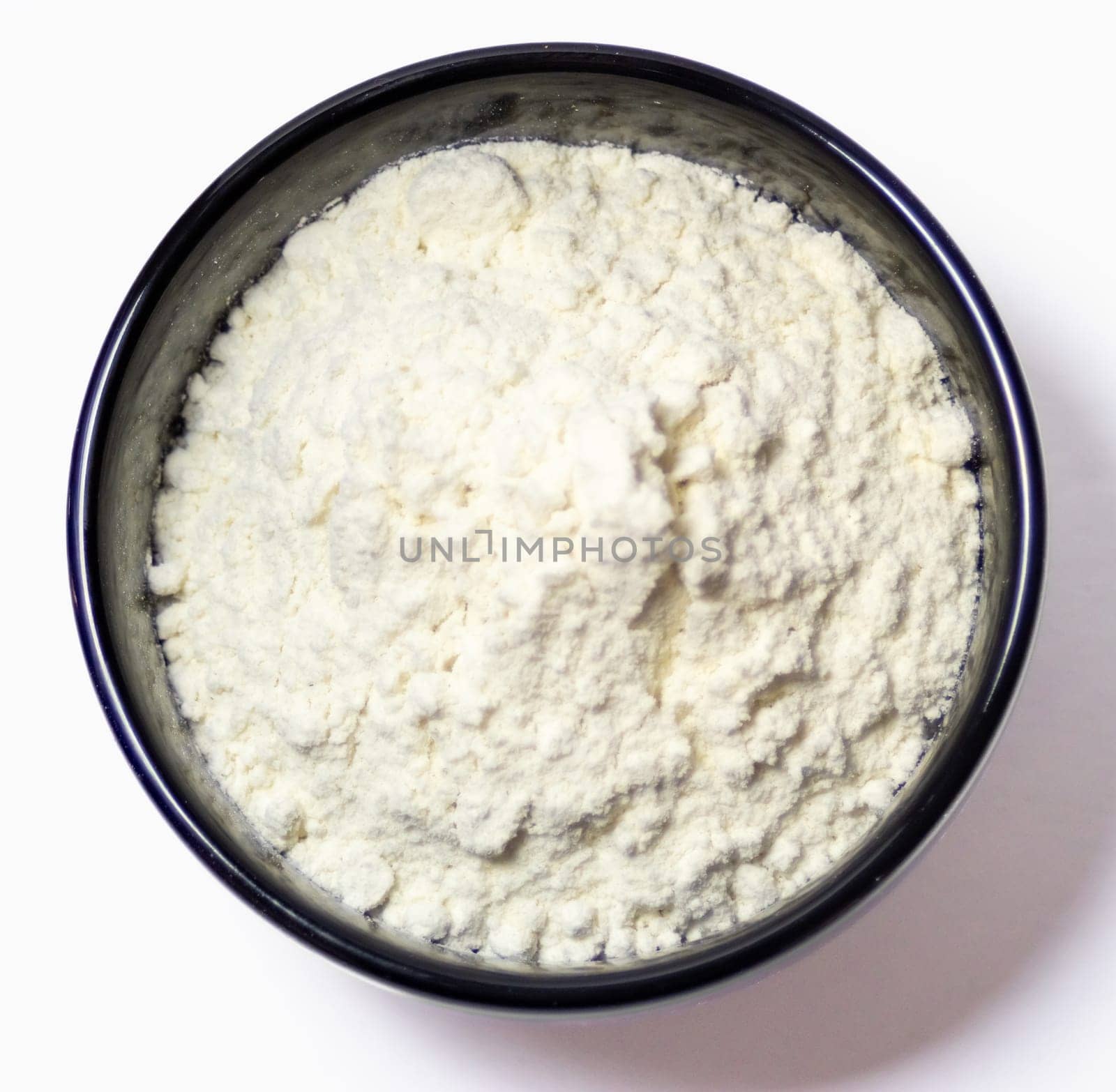 Zenithal picture of a black bowl containing flour. Ingredient for preparing cakes and pastries. Close-up photo