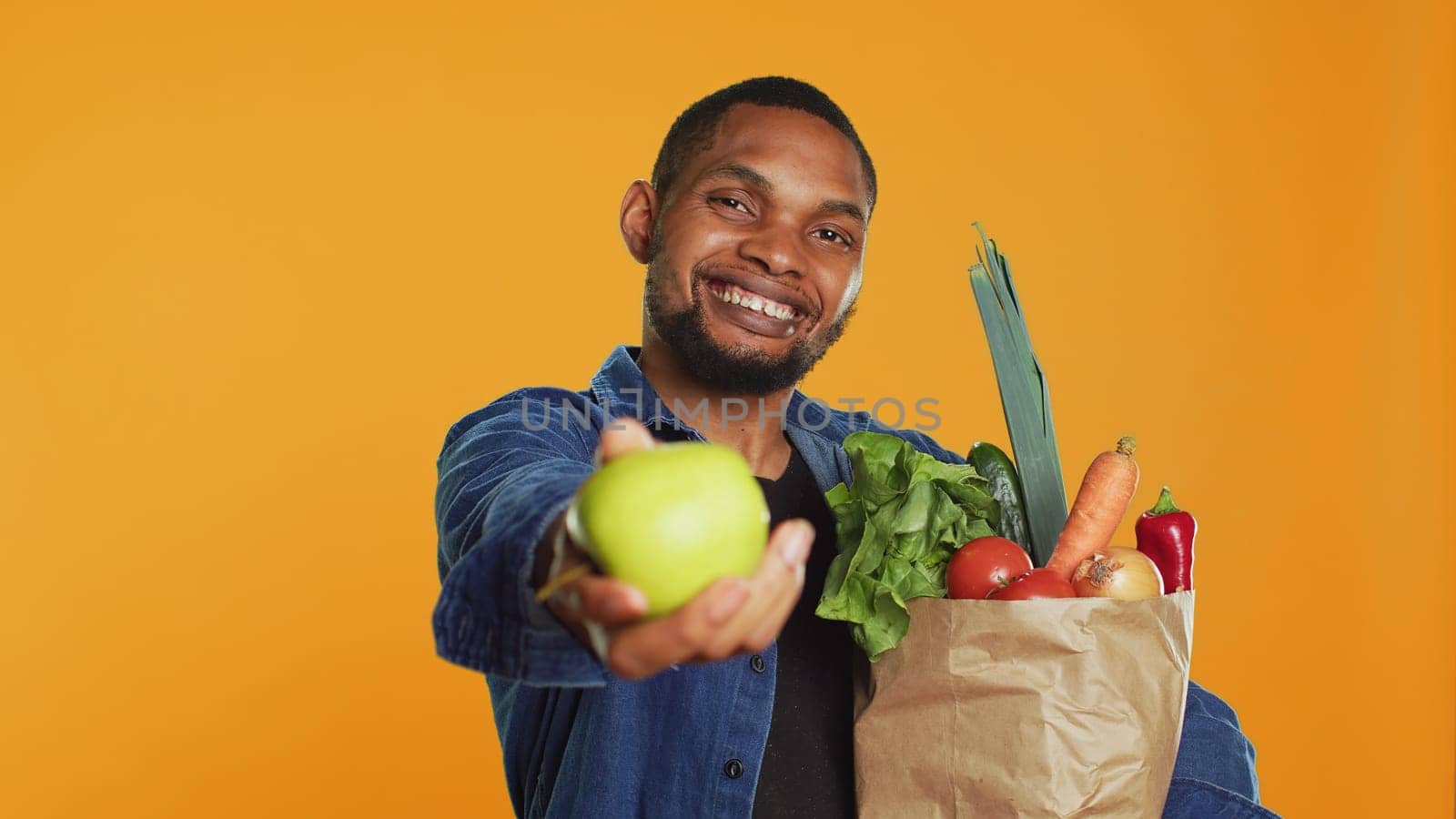 African american man presenting a freshly harvested green apple by DCStudio