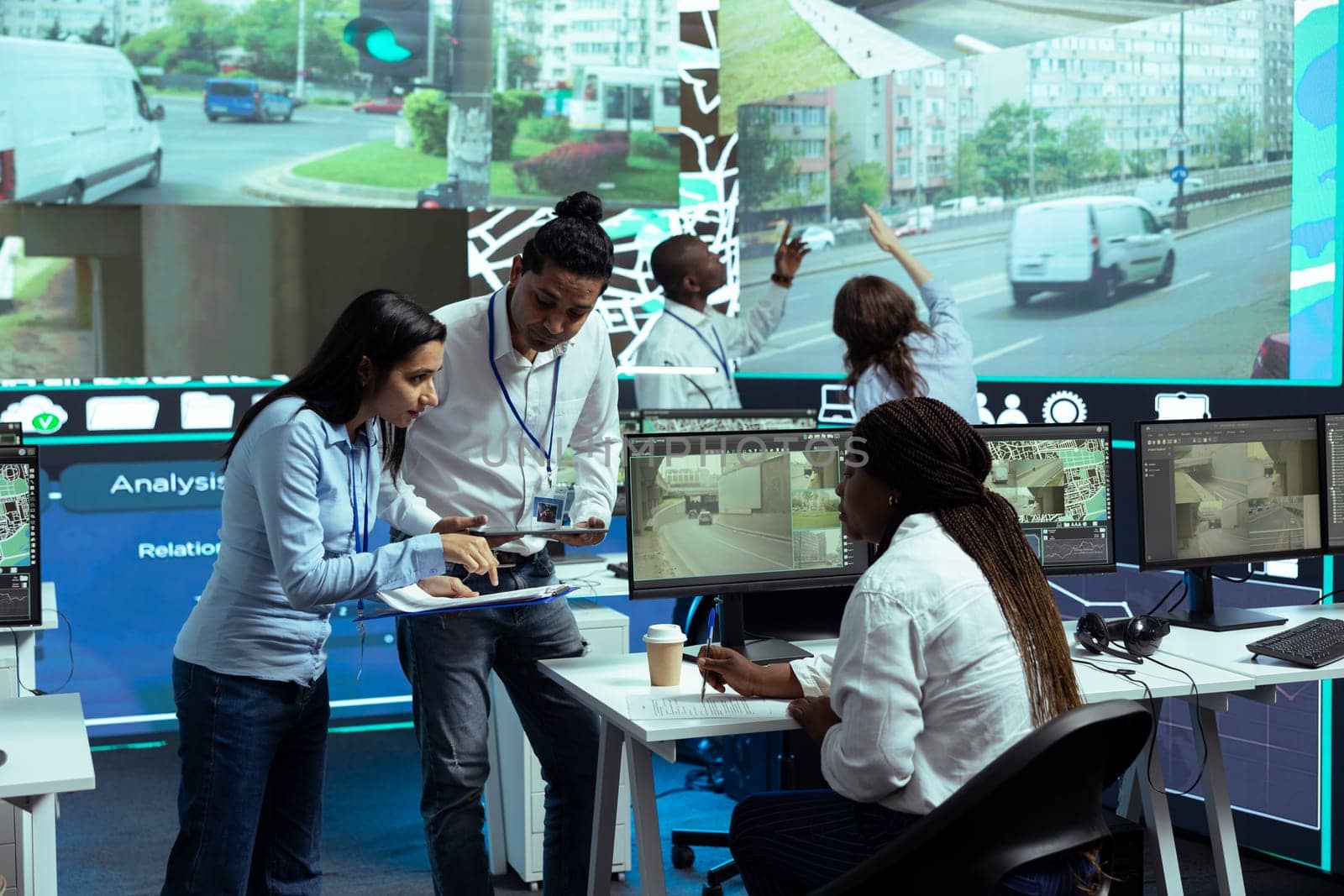 Indian supervisors explaining cargo logistics and destination to an operator, using CCTV surveillance cameras footage to trace delivery trucks around town. Express shipment via gps.