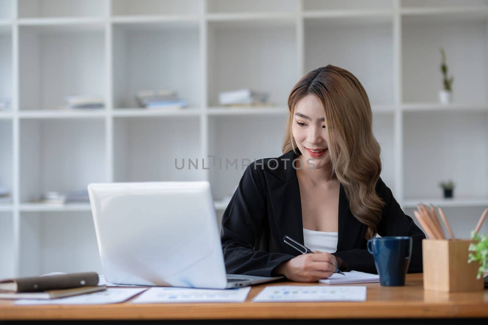 Beautiful accountant sitting working with laptop calculating financial and tax figures for company on desk in living room..