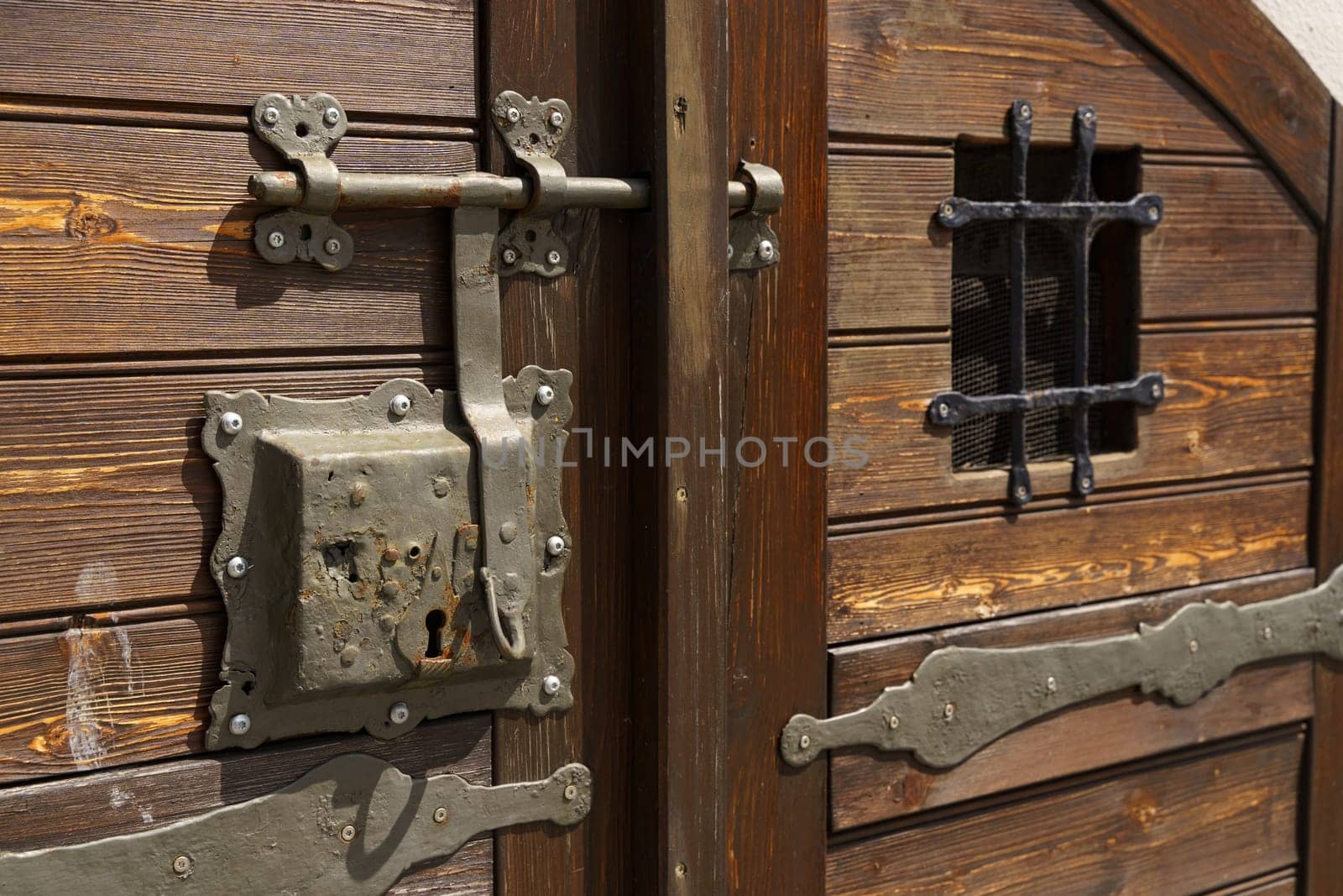 A close-up shot of an intricate iron lock and latch on a weathered wooden door.