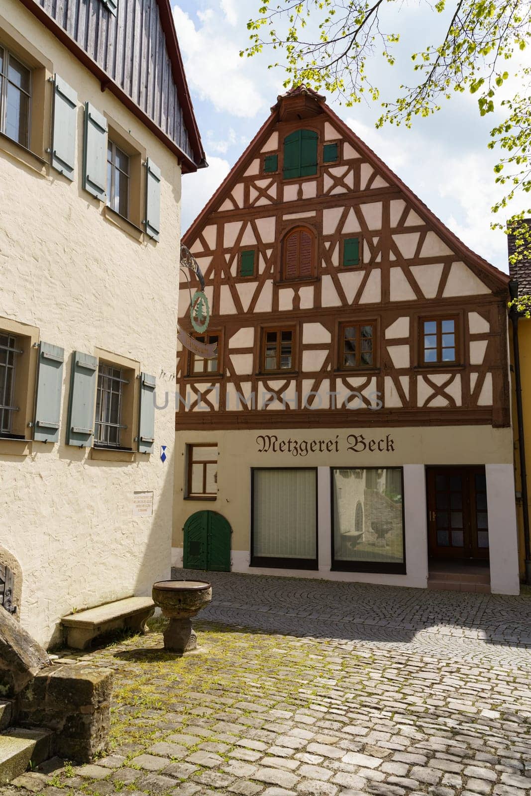 Feuchtwangen, Germany - June 6, 2023: A traditional butcher shop with a sign that reads Metzgerei Beck is located in a charming cobblestone alleyway in Germany. The buildings timber framing and decorative details are a beautiful example of the regions architectural style.