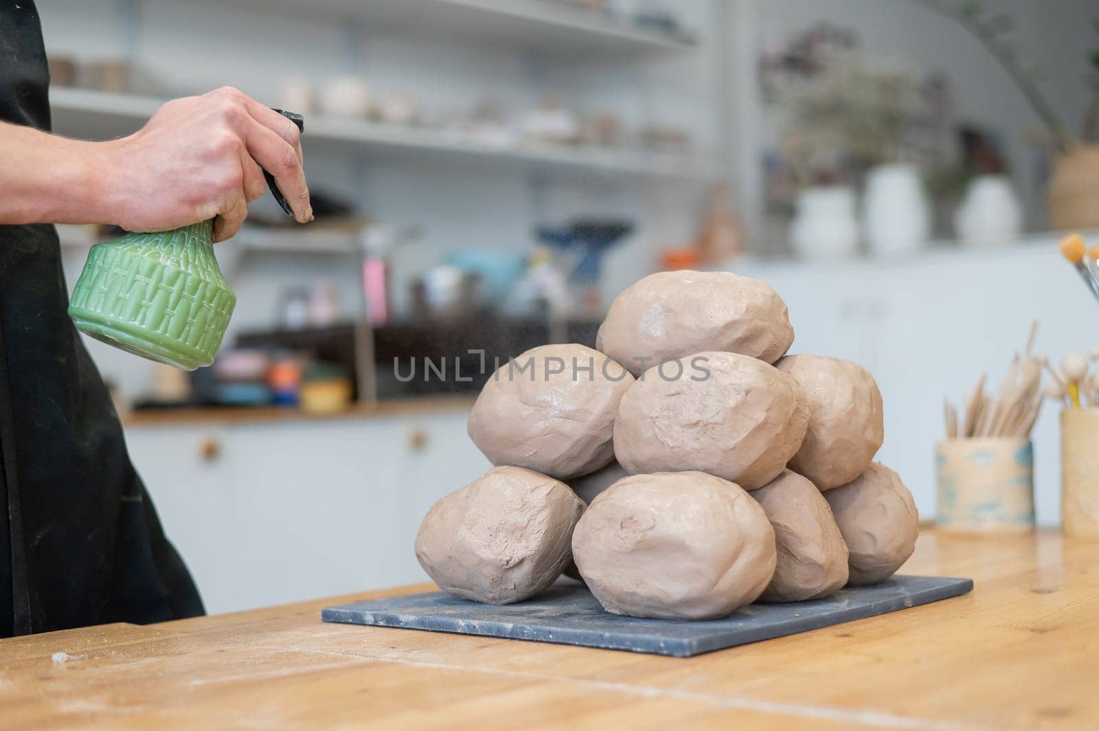 The potter wets the clay before using it in the workshop