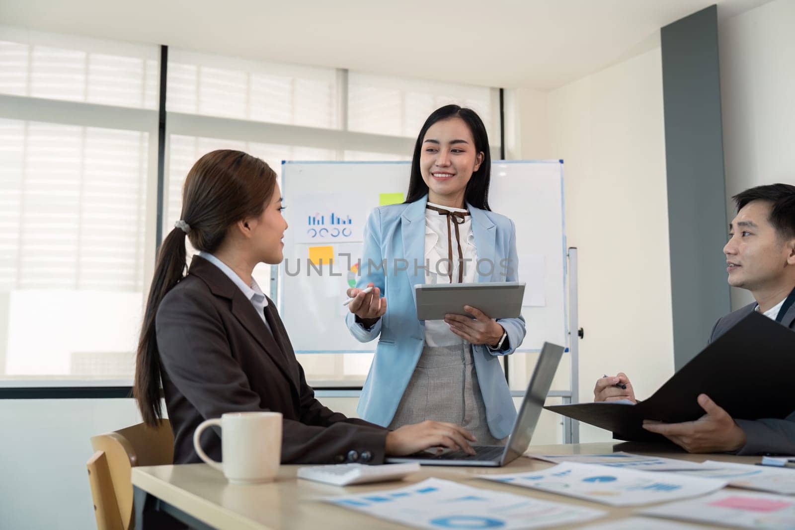 Business team engaging in a strategy meeting using a tablet in a modern office setting, emphasizing leadership, teamwork, and effective communication