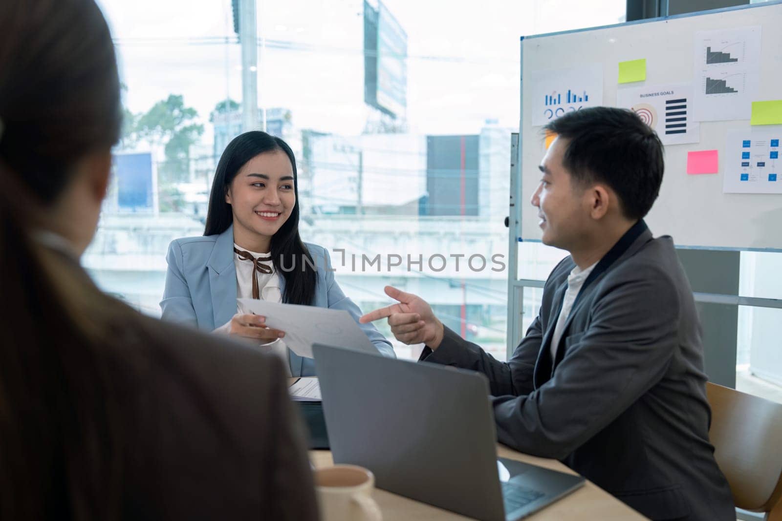 Business team engaged in a strategy discussion with documents and laptops in a modern office setting, highlighting leadership, teamwork, and effective communication