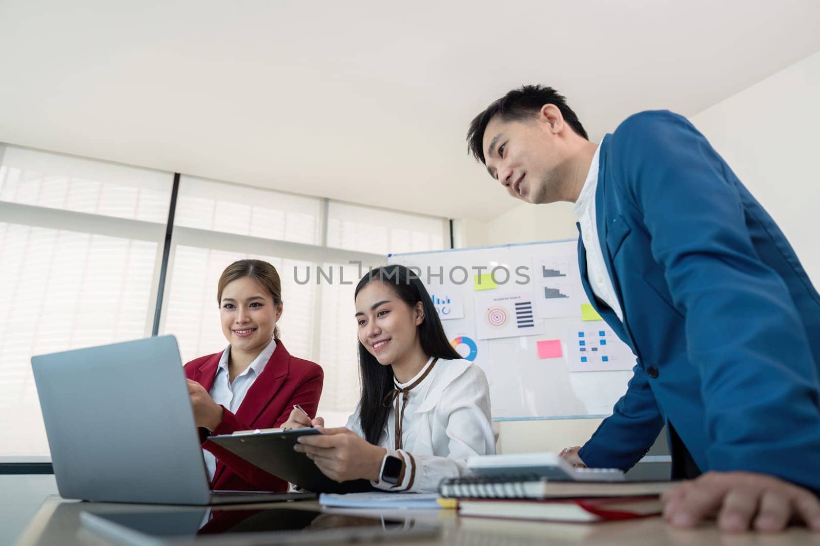 Business team collaborating on a project using a laptop in a modern office setting, showcasing teamwork and productivity