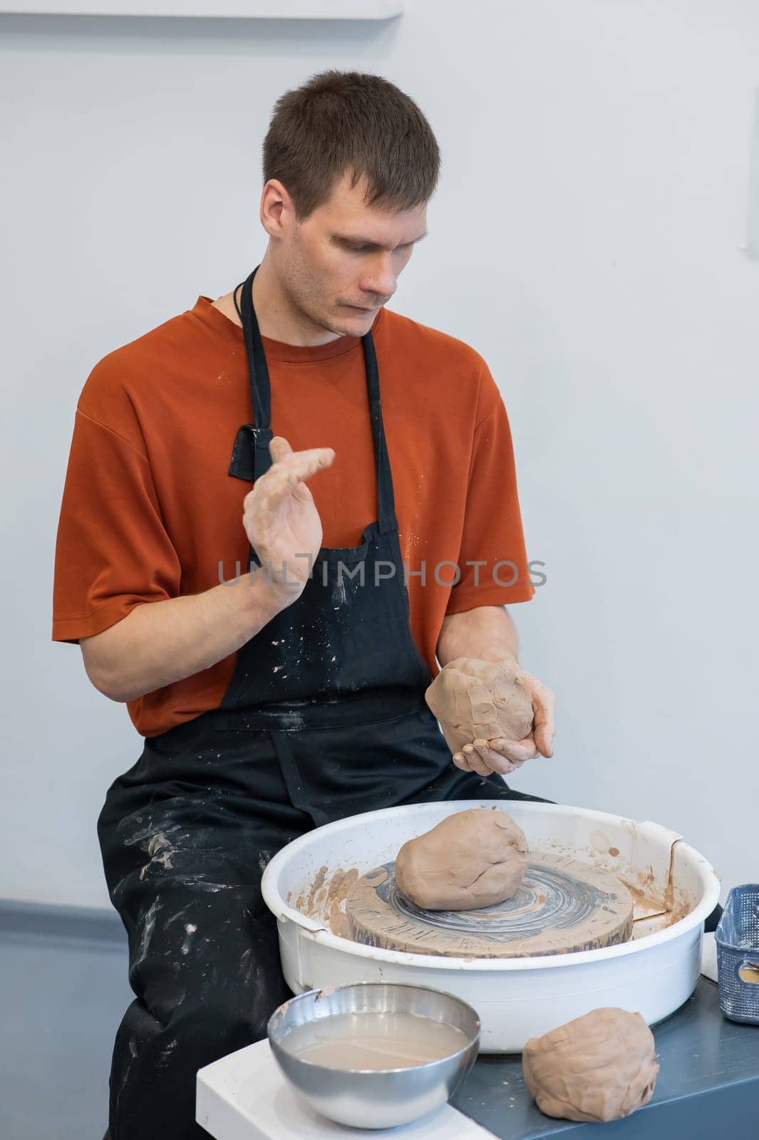 A potter kneads clay before using it on the potter's wheel. Vertical photo. by mrwed54