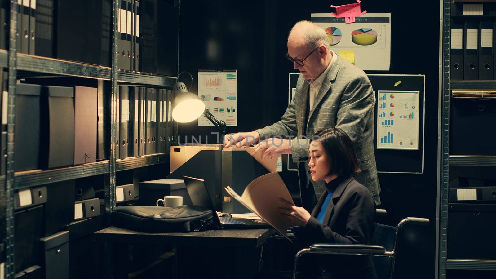 Wheelchair user and inspector analyzing criminal records in police archive room by DCStudio