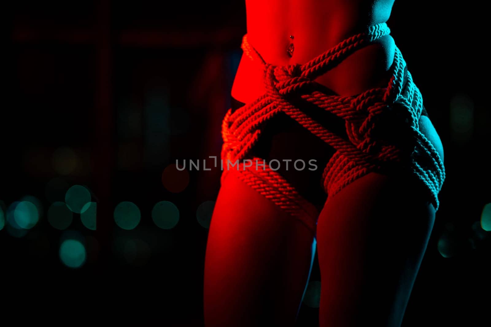 Close-up of a woman's belly in ropes tied using the Japanese shibari technique