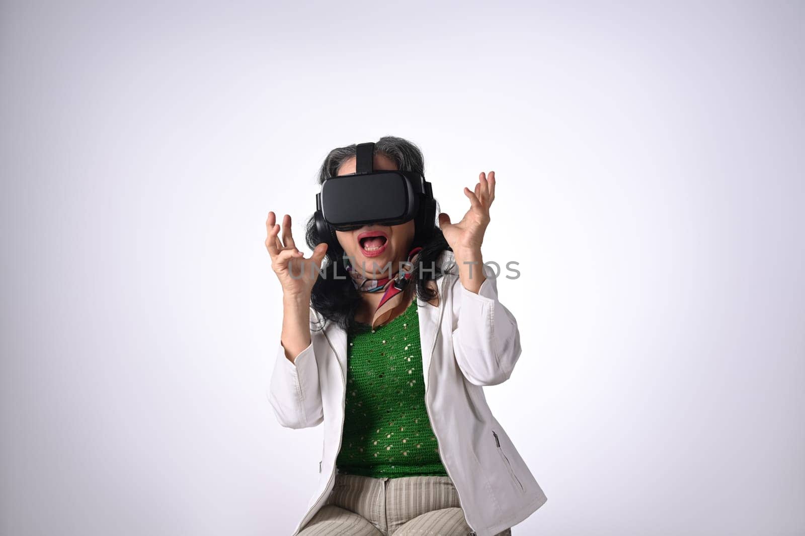 Amazed senior woman VR headset enjoying virtual reality experience isolated on white background.