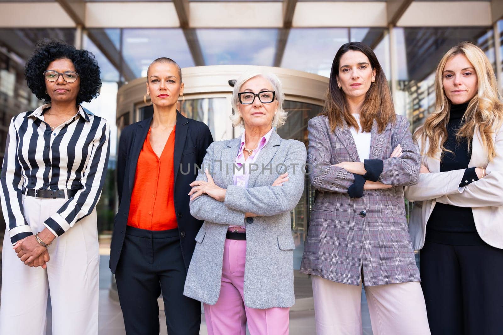 Five businesswomen standing side by side with their arms crossed looking at the camera serious. Suitable for team, friendship and diversity concepts.