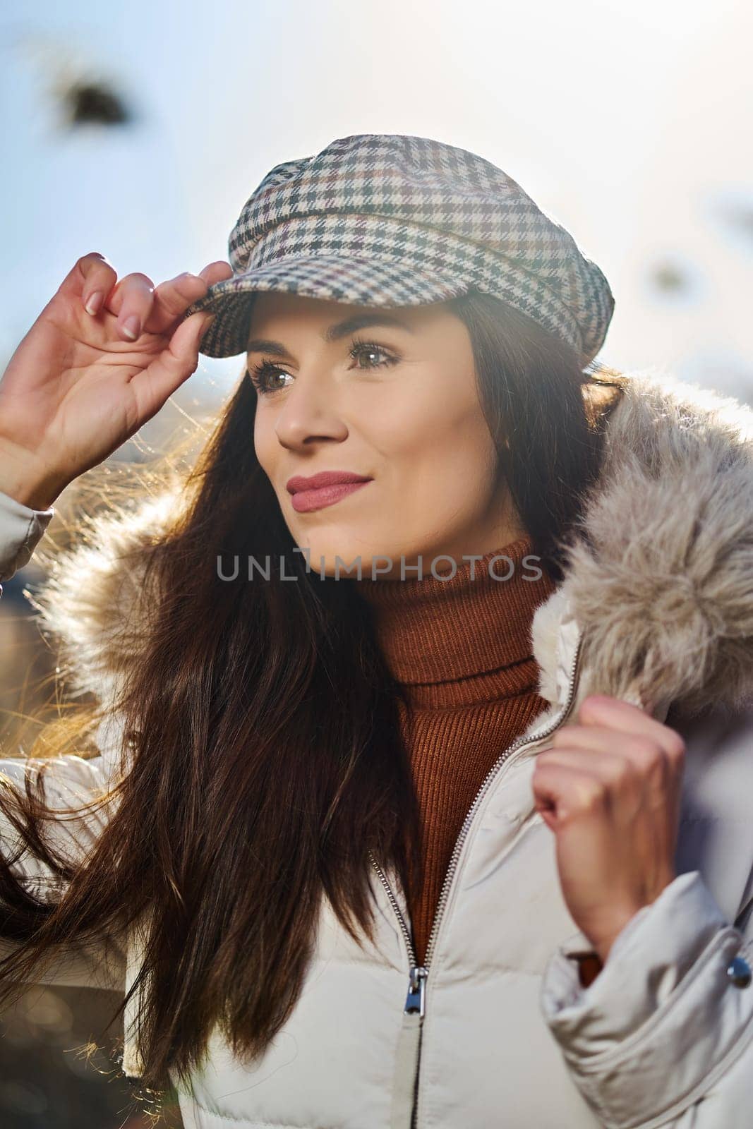 Beautiful young brunette woman in jacket poses on meadow on sunny day