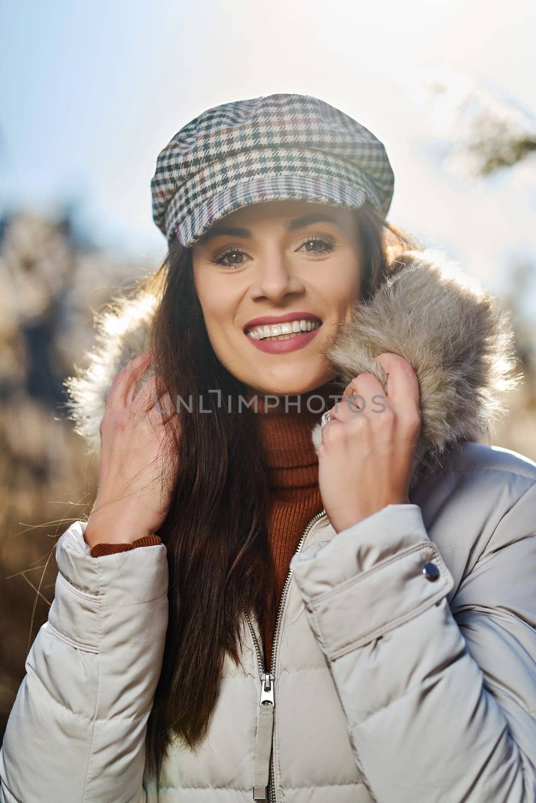 Beautiful young brunette woman in jacket poses on meadow on sunny day