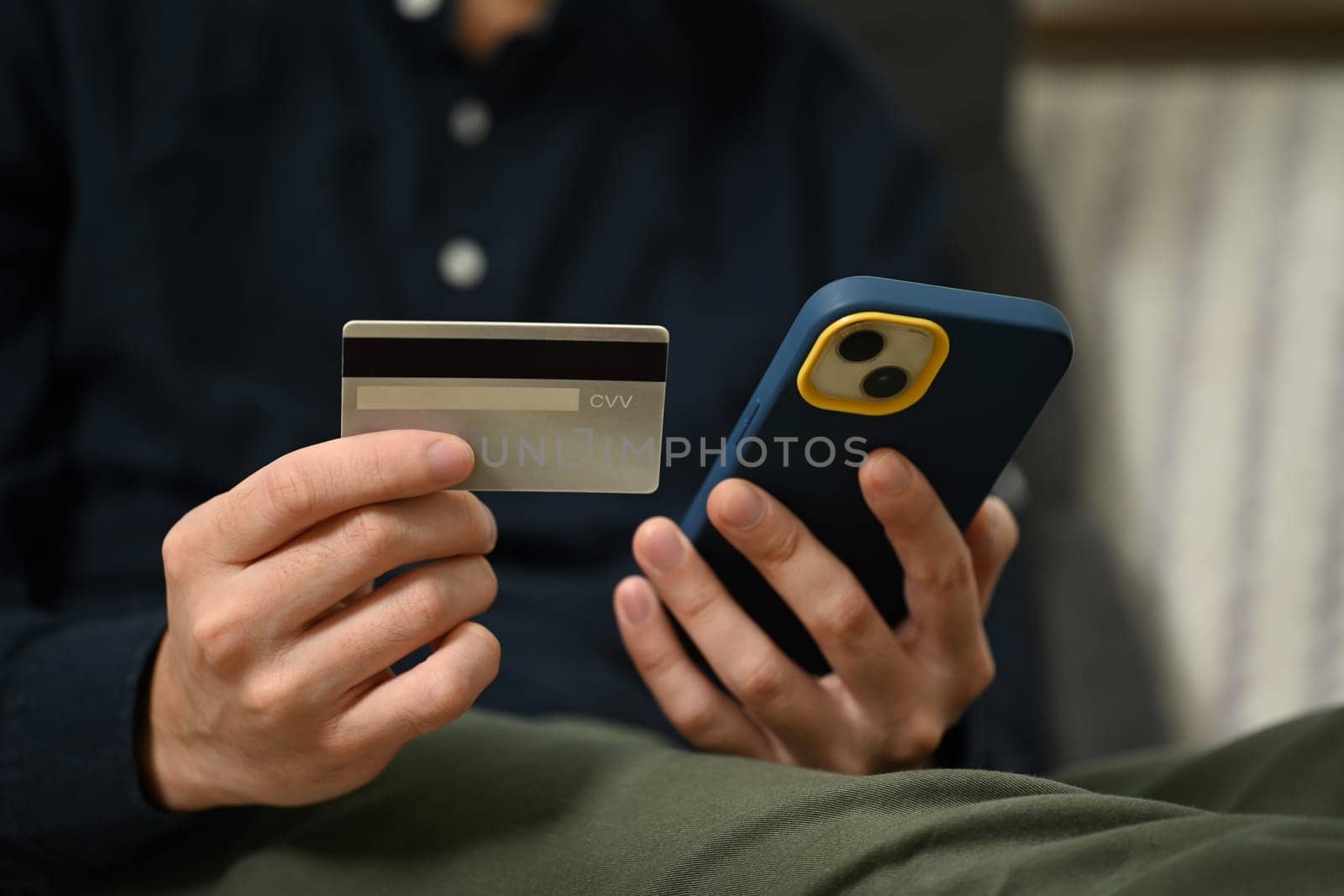 Man holding credit card making payment on mobile phone. Internet banking and shopping online concept.