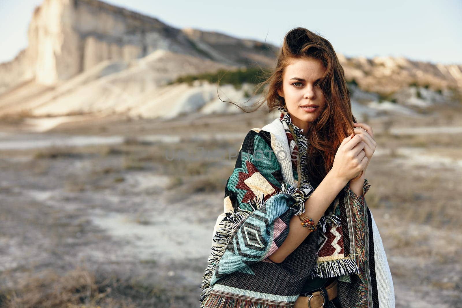 Desert oasis woman in traditional garb stands in front of majestic mountain view