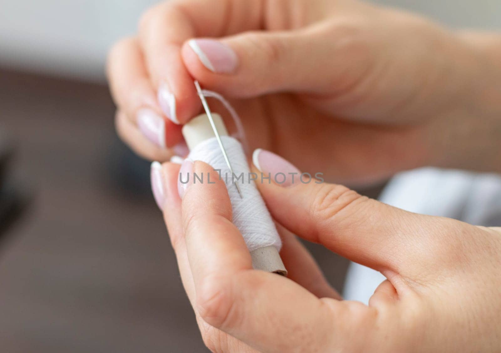 Shot of the woman with beautiful hands stitching up or patching a linen fabric