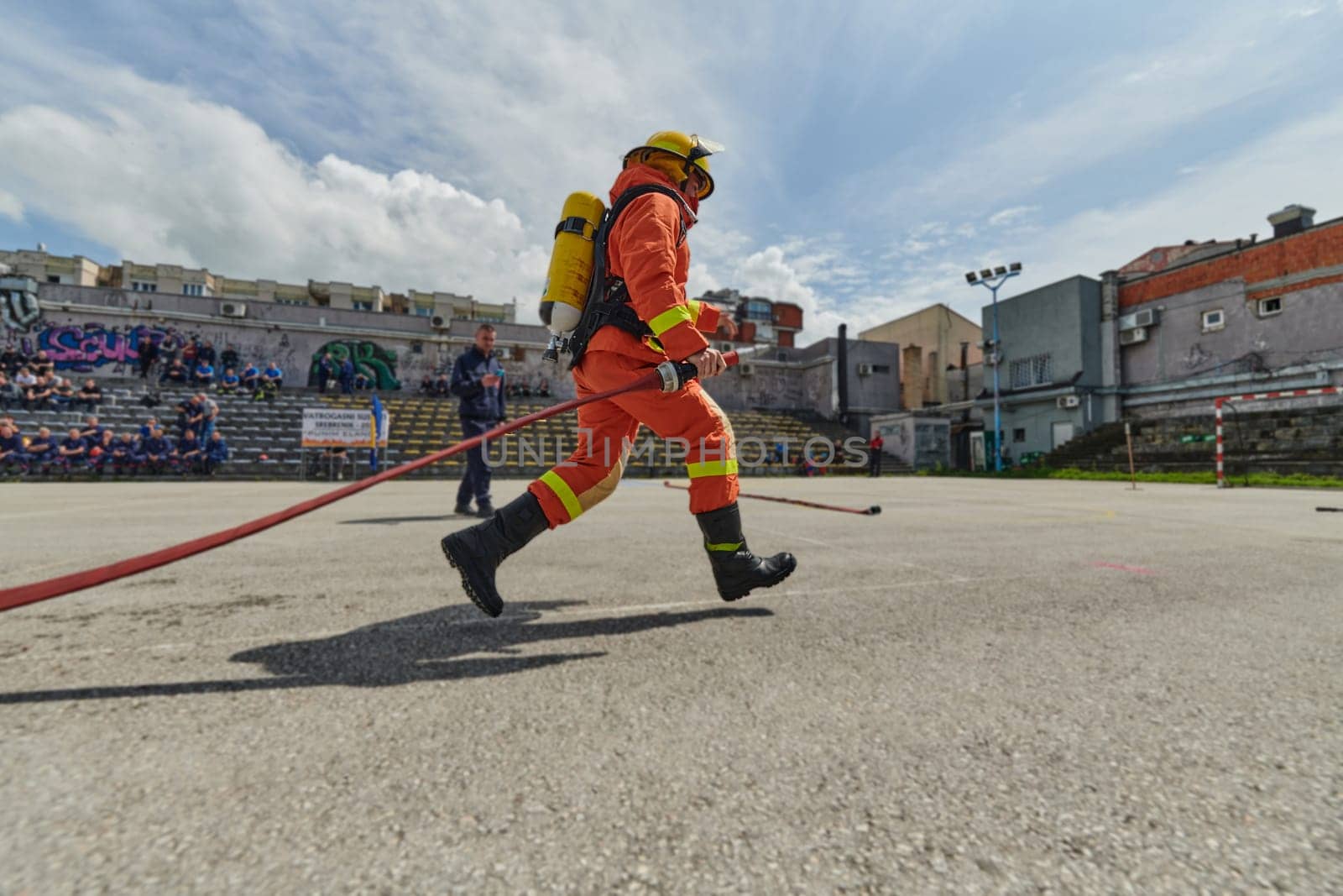 In a dynamic display of synchronized teamwork, firefighters hustle to carry, connect, and deploy firefighting hoses with precision, showcasing their intensive training and readiness for challenging and high-risk situations ahead by dotshock