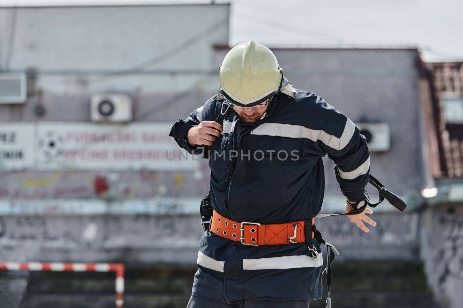 A firefighter dons the essential components of their professional gear, embodying resilience, commitment, and readiness as they gear up for a hazardous firefighting mission, a testament to their unwavering dedication to protecting and saving lives.