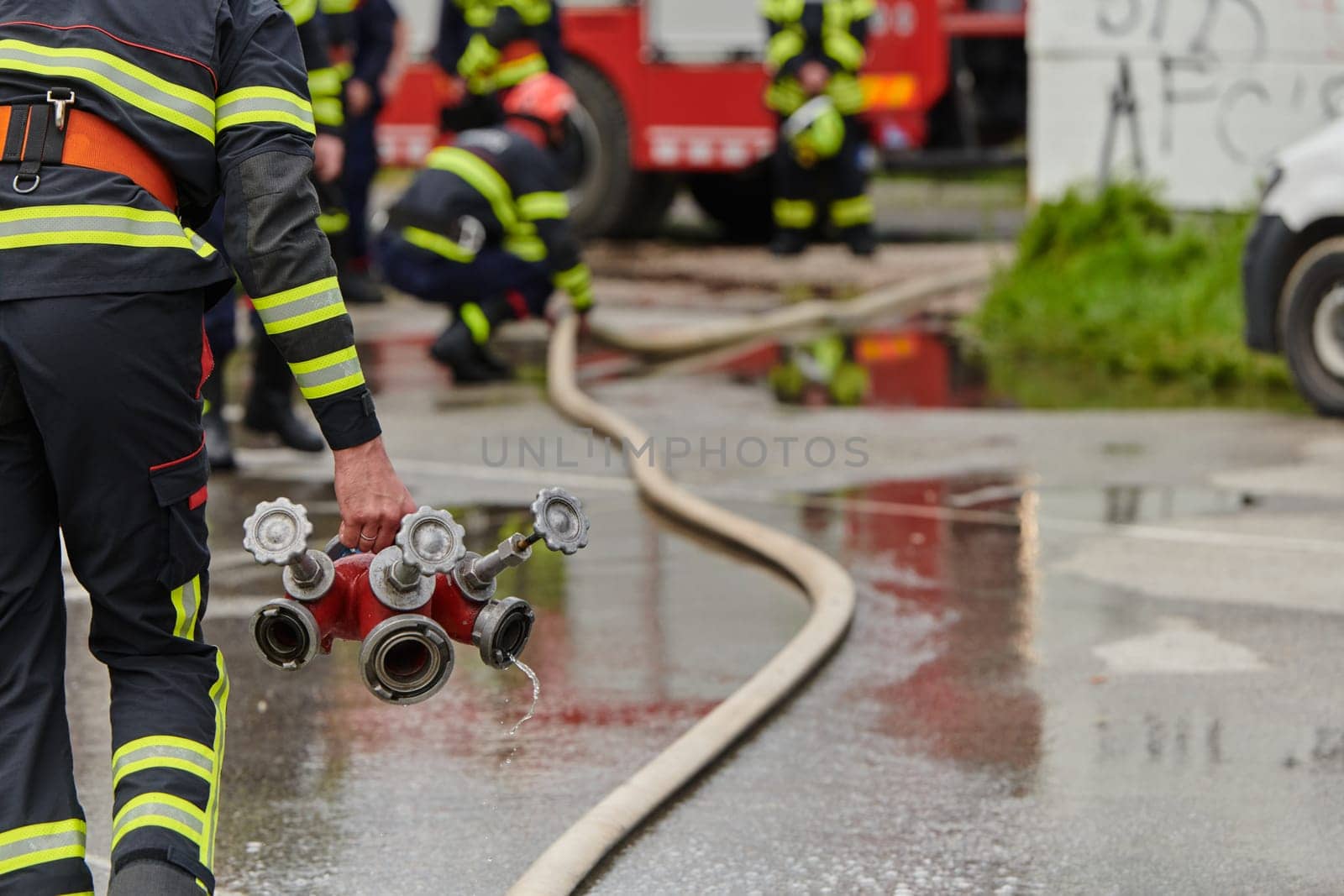 In a dynamic display of synchronized teamwork, firefighters hustle to carry, connect, and deploy firefighting hoses with precision, showcasing their intensive training and readiness for challenging and high-risk situations ahead.