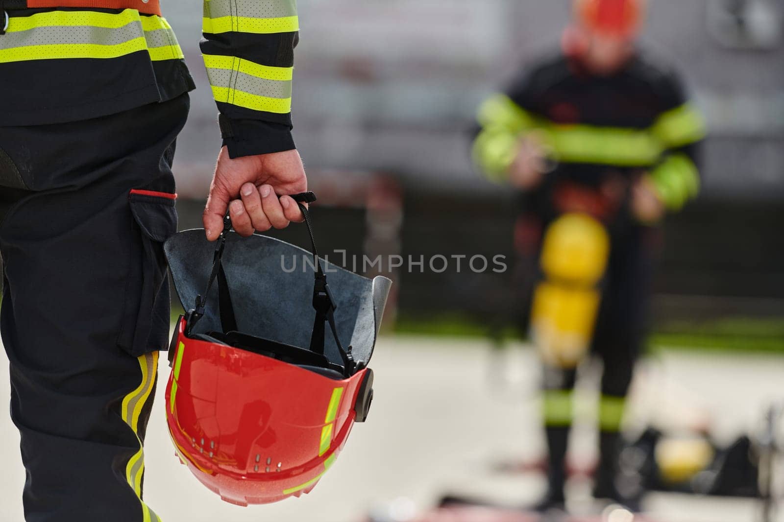 A close up shot capturing the hand of a firefighter holding a fire helmet with a strong sense of readiness and determination.