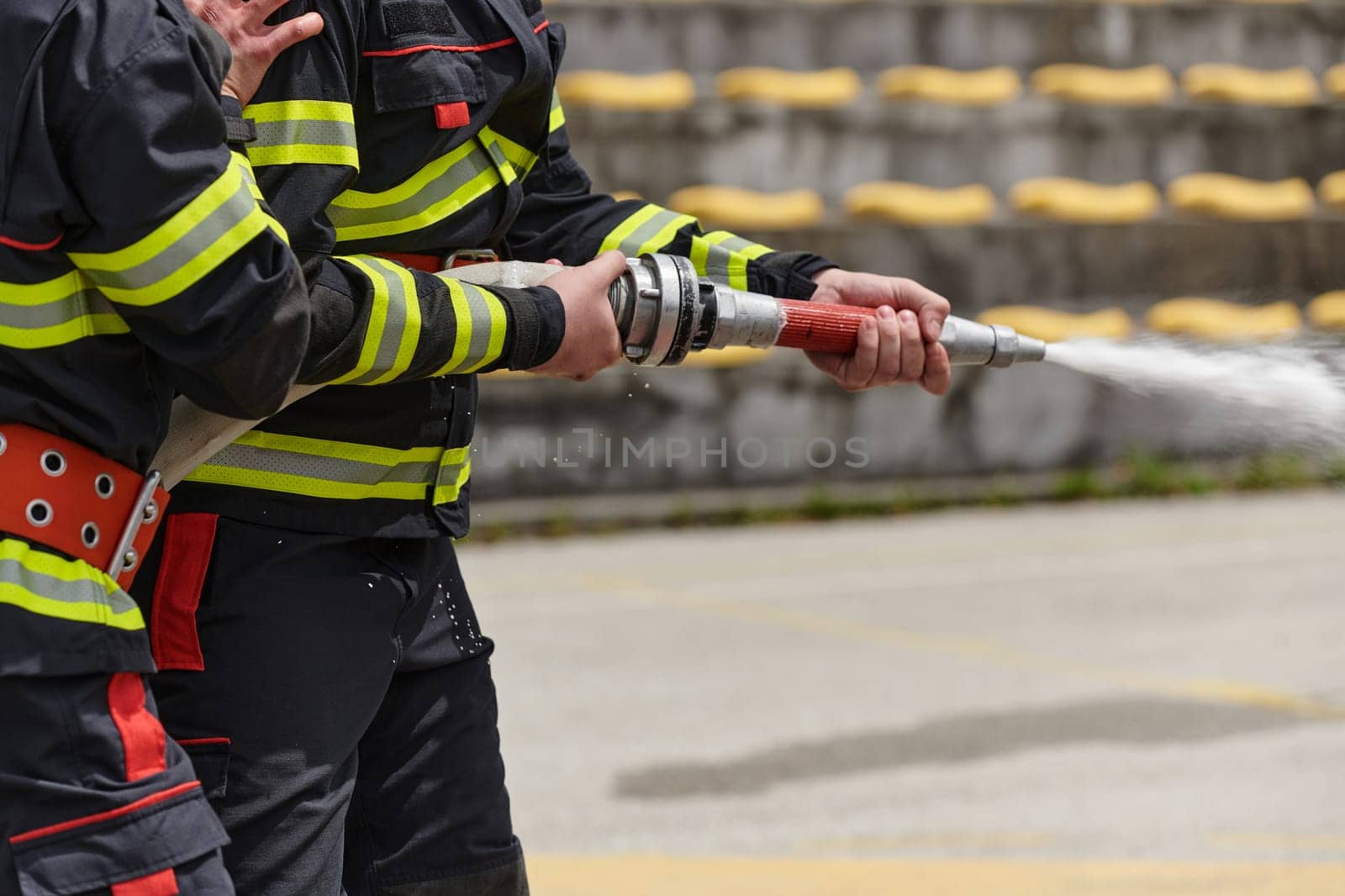 A team of professional firefighters undergoes training on the proper usage of a water hose for firefighting operations