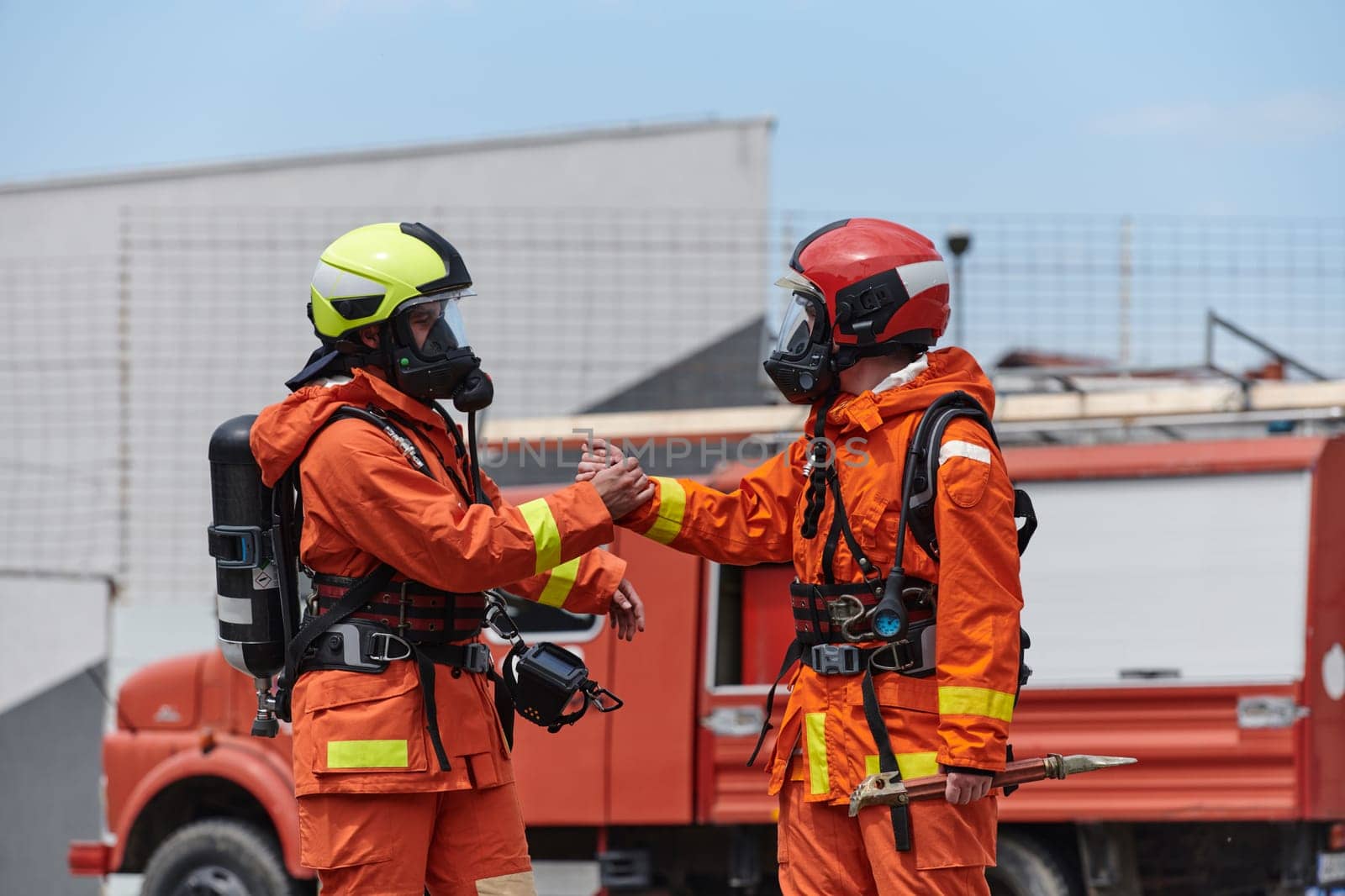 A unified team of firefighters, adorned in their uniforms, engages in a heartfelt celebration marked by triumphant salutes and cheers, embodying the joy and gratitude following the successful completion of a challenging firefighting mission.