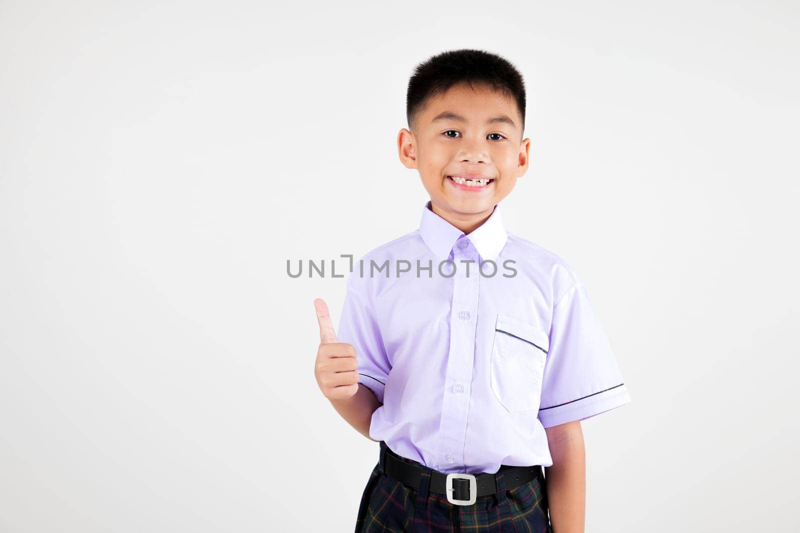 Portrait smile Asian little boy primary posing giving a thumbs up studio isolated white background, happy cute man kid wear school uniform plaid is expressing his approval by Sorapop