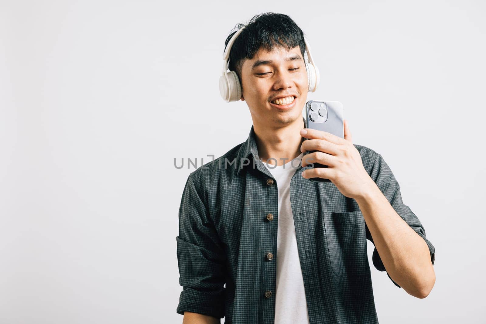 A man's happy karaoke moment unfolds as he listens to music on his smartphone by Sorapop