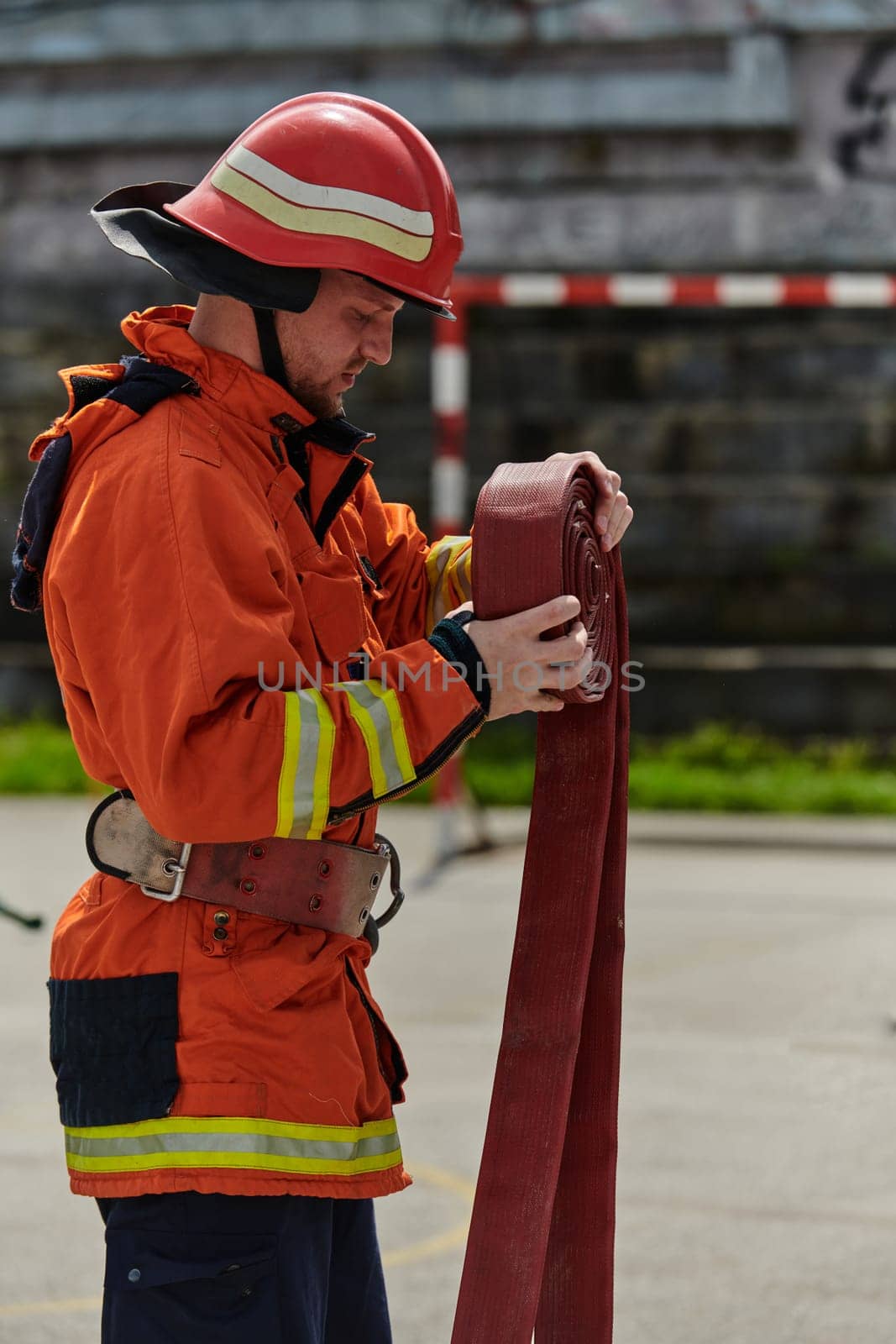 A dedicated firefighter meticulously coils the fire hose after successfully extinguishing a blaze, showcasing the critical post-incident responsibilities.