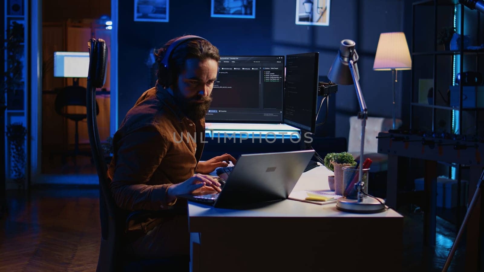 Developer typing code in home office, using Java programming language to develop software application. It professional using multimonitor PC setup and laptop to finish tasks, camera B