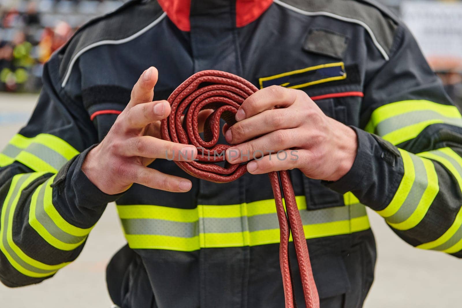 A dedicated firefighter meticulously coils the fire hose after successfully extinguishing a blaze, showcasing the critical post-incident responsibilities.