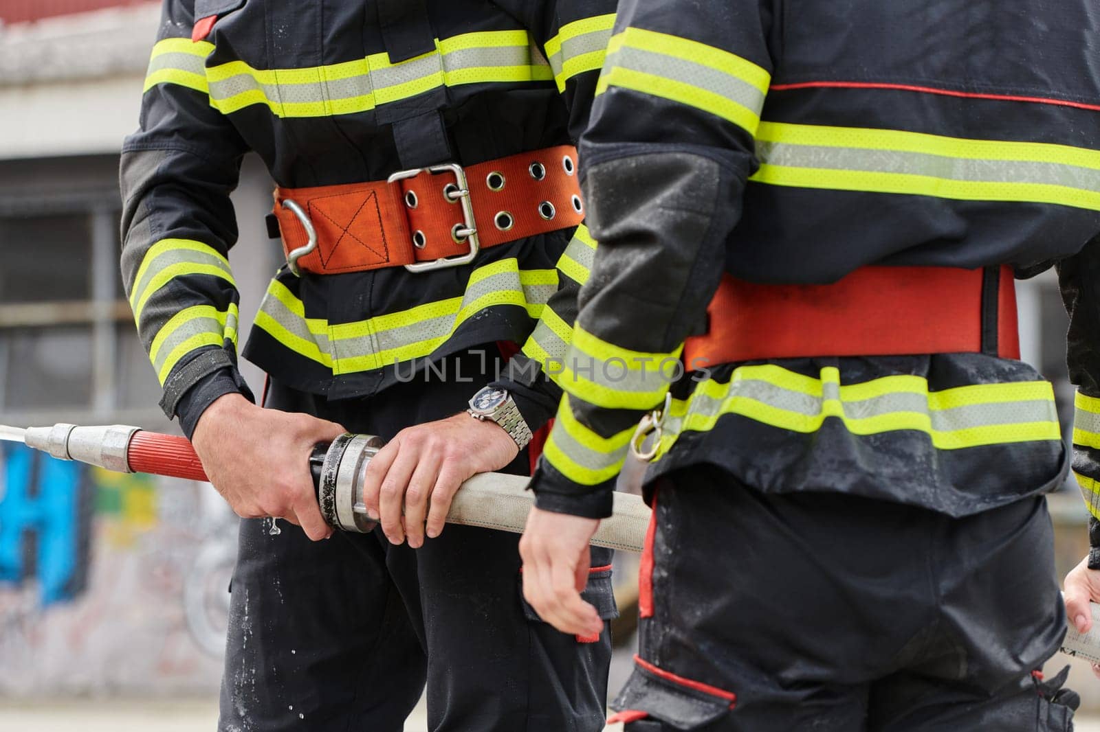 In a dynamic display of synchronized teamwork, firefighters hustle to carry, connect, and deploy firefighting hoses with precision, showcasing their intensive training and readiness for challenging and high-risk situations ahead.