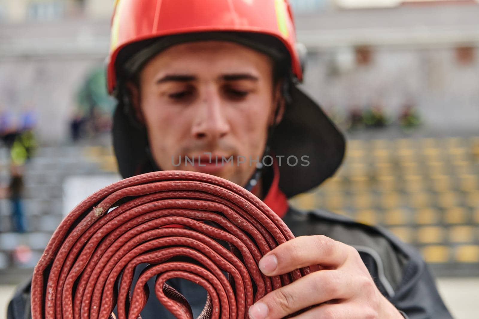 A dedicated firefighter meticulously coils the fire hose after successfully extinguishing a blaze, showcasing the critical post-incident responsibilities.